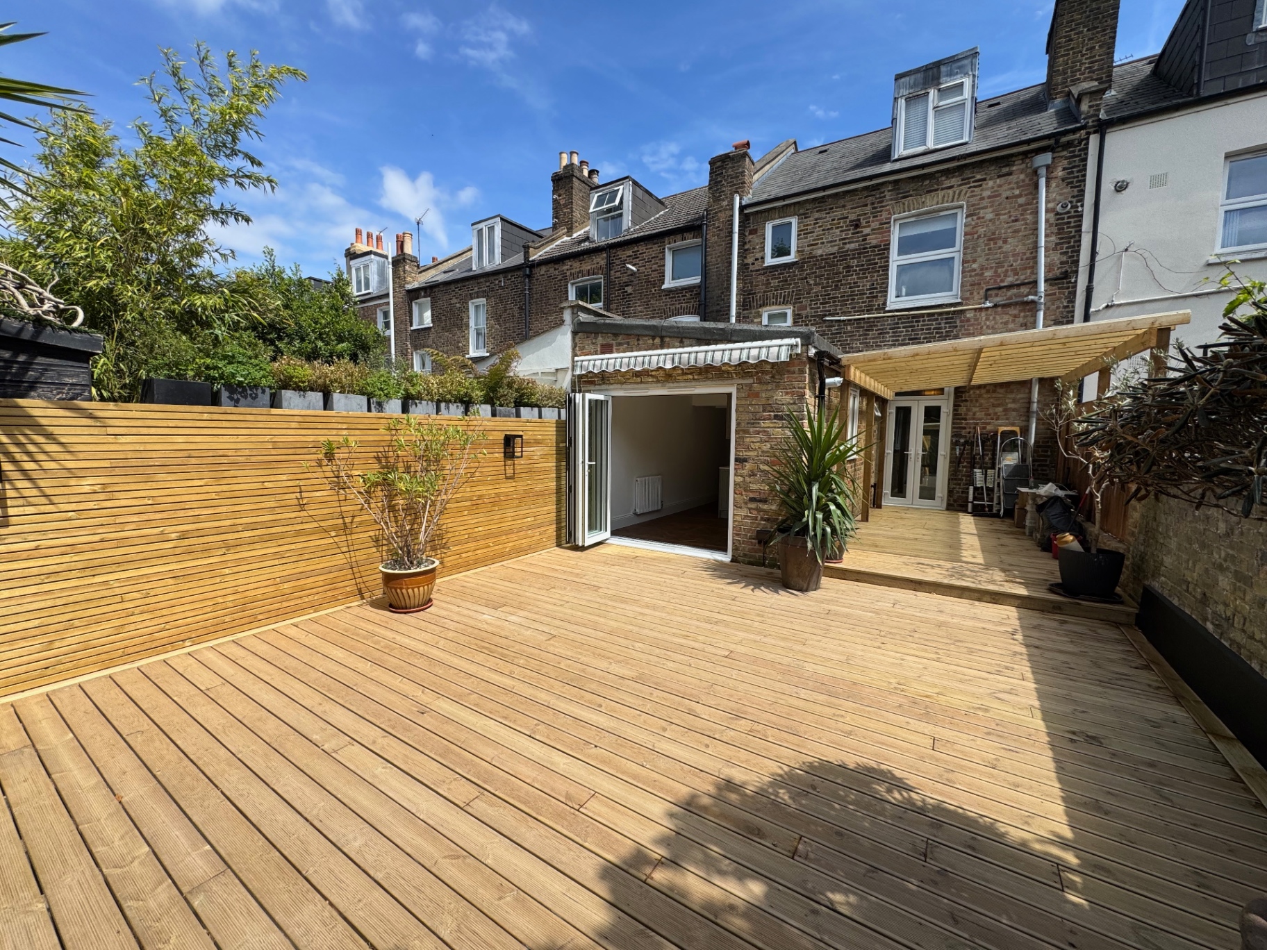 Wide view of the new rear deck with slatted timber fencing and planting