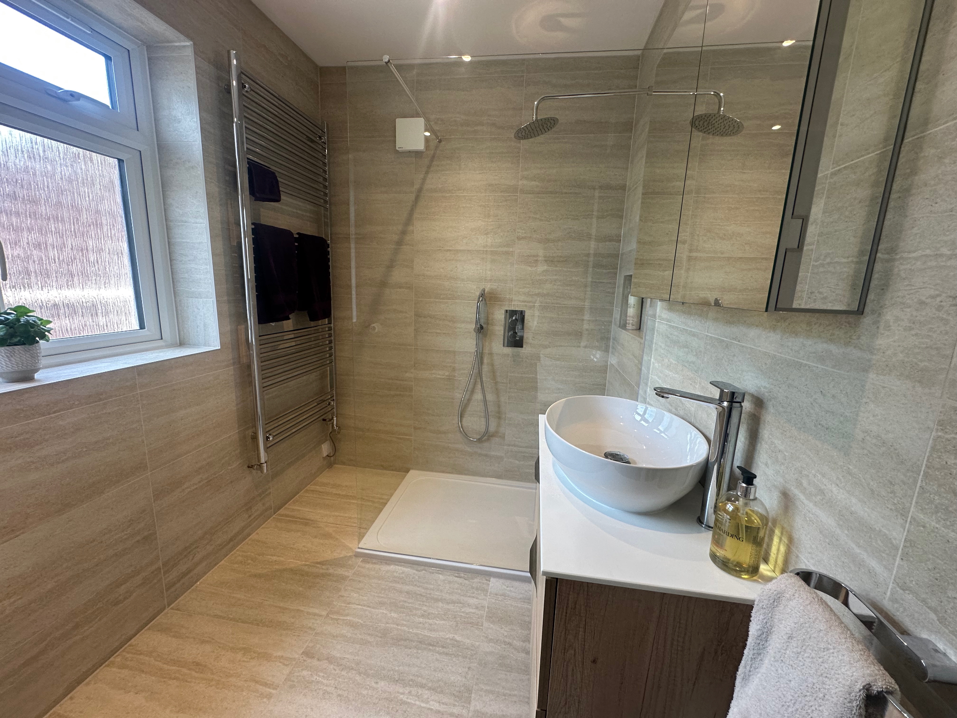 Generous walk-in shower with rainfall head, frameless glass screen and stone tiling