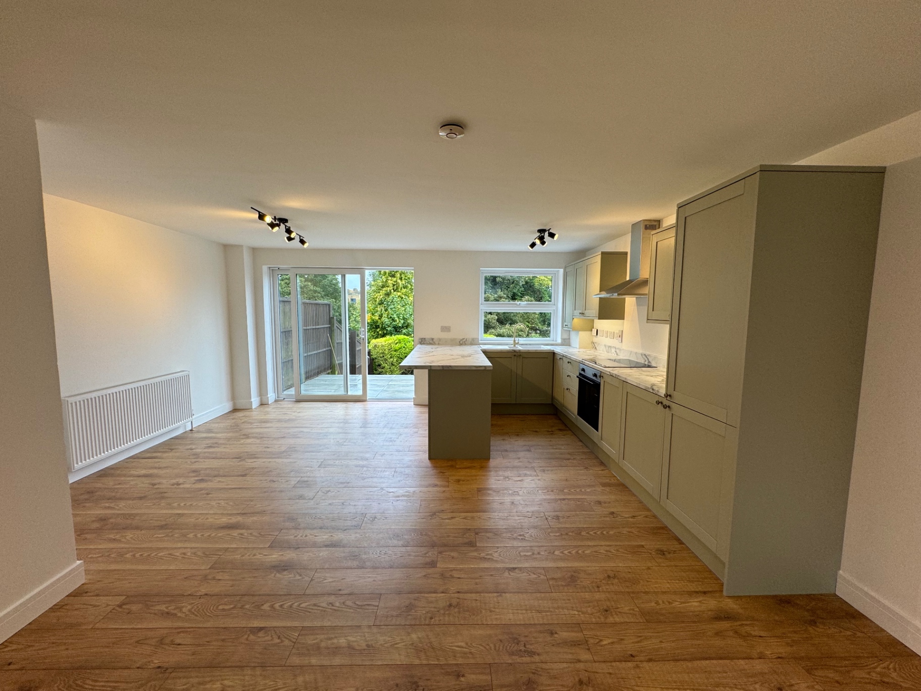 Open-plan room showing the kitchen alongside the living space and garden doors