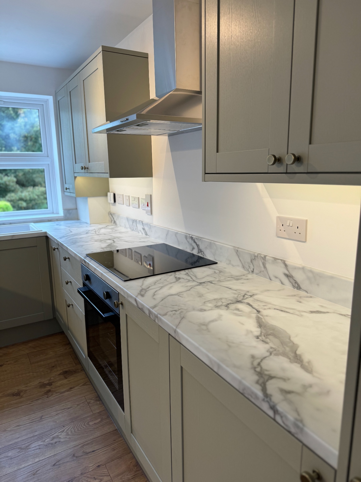 Induction hob, oven and marble-effect worktop run with stainless extractor