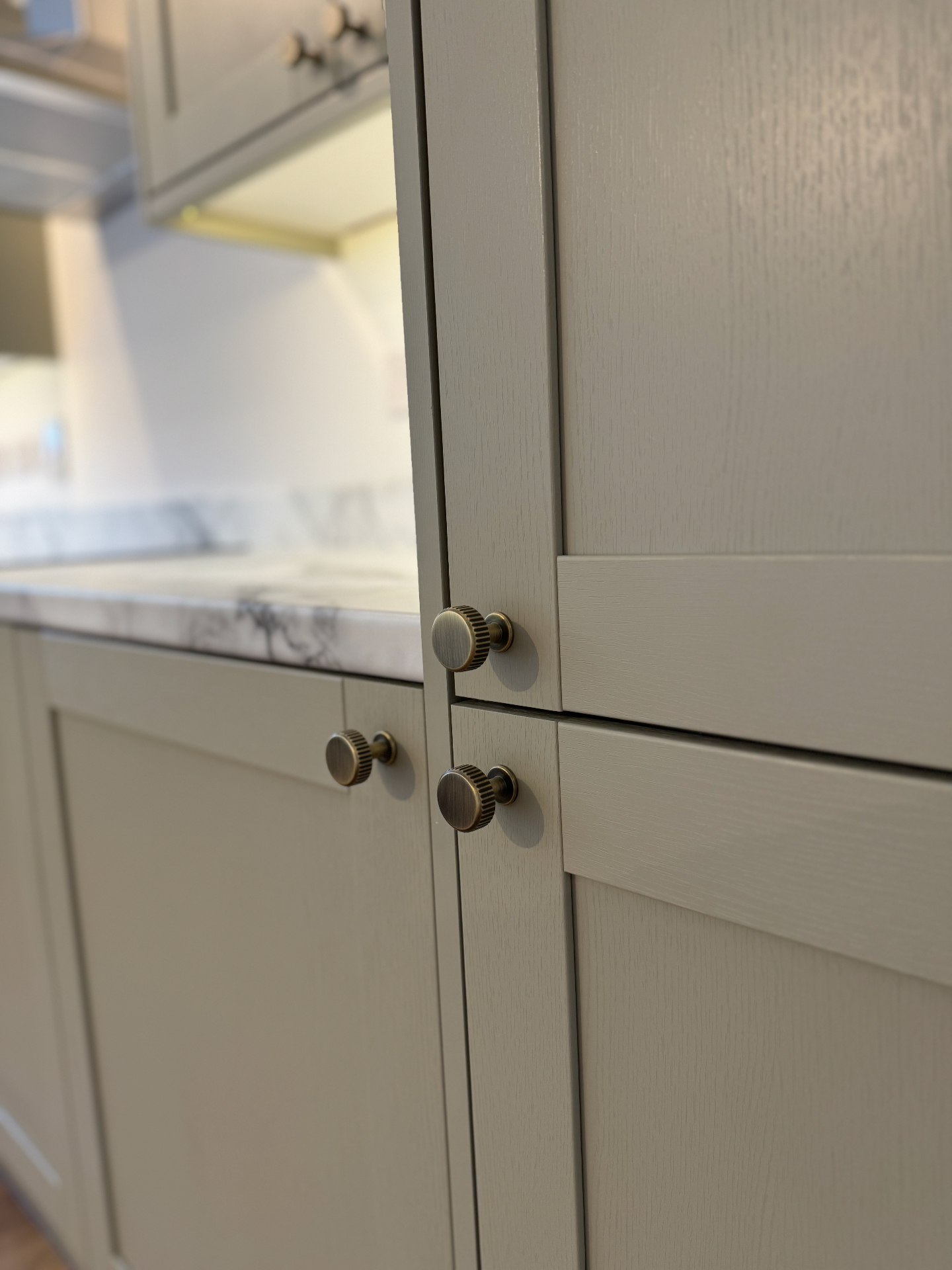 Close detail of sage shaker doors with brass knurled cabinet knobs