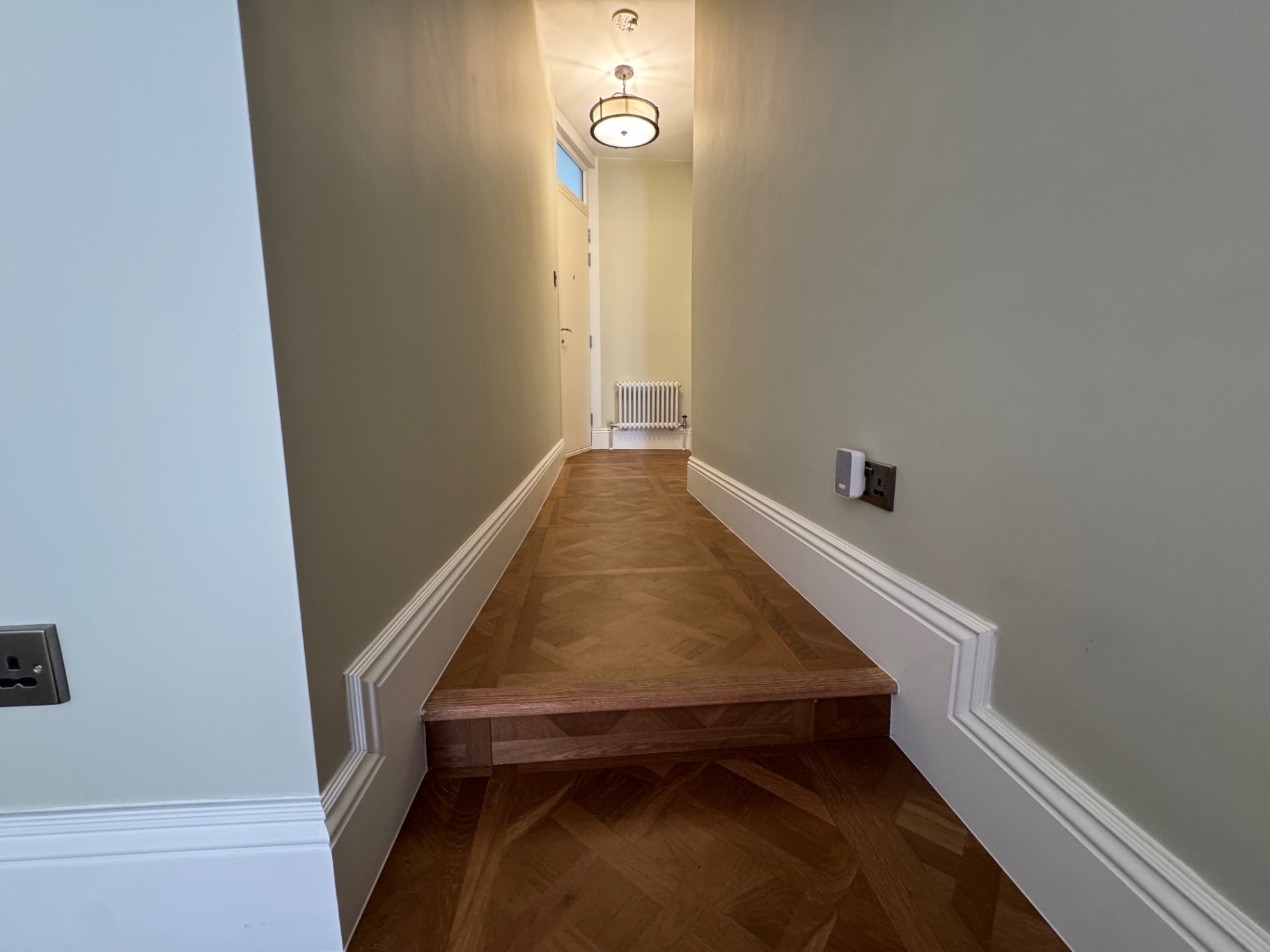 Renovated hallway with parquet-style flooring, traditional skirting and a timber step