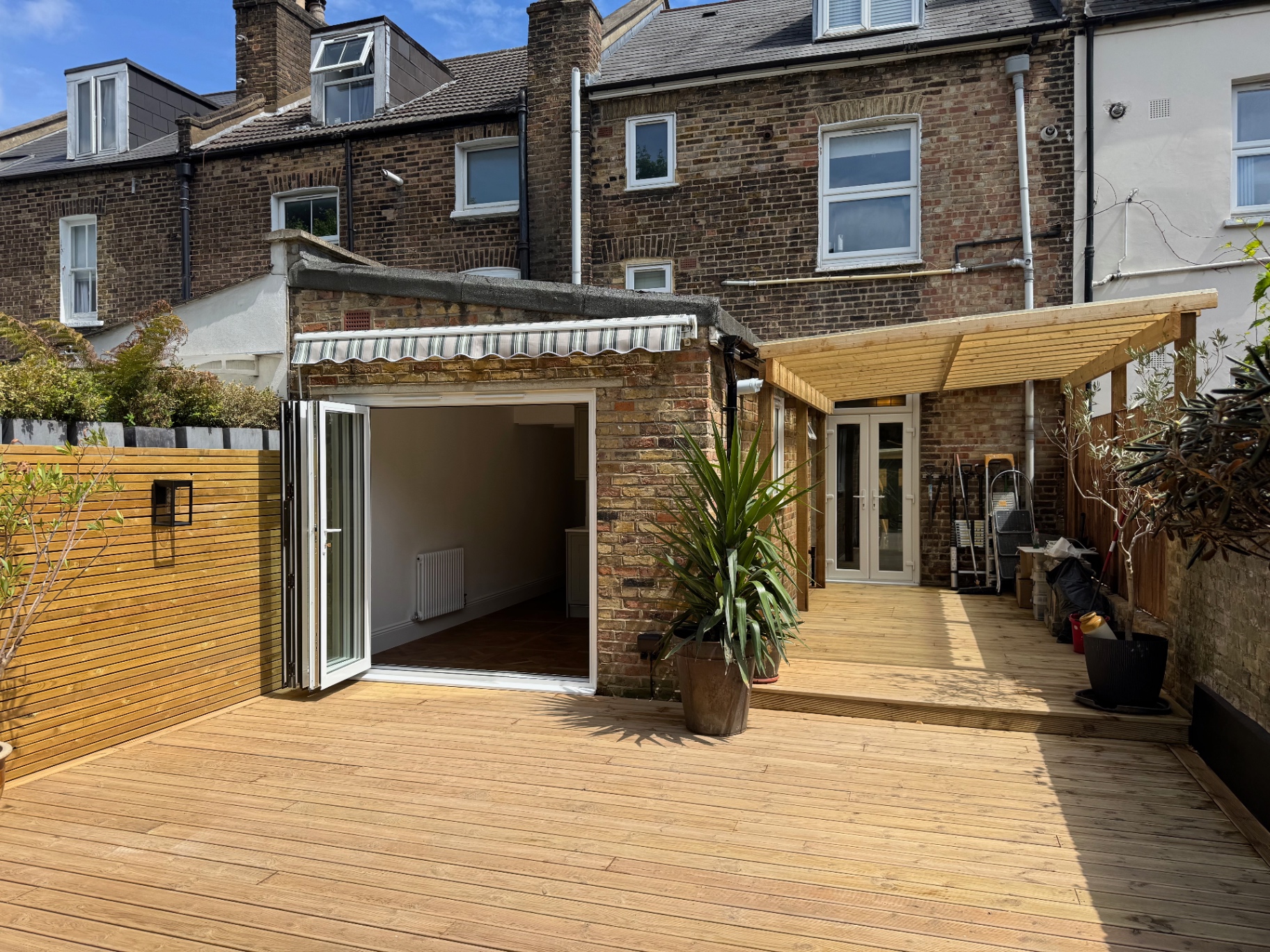 Rear elevation with new timber decking, pergola and bi-fold doors open to the garden
