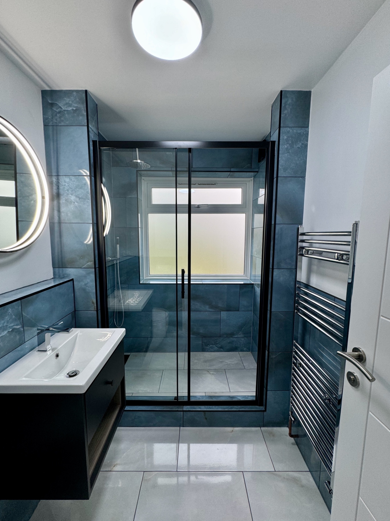 Straight-on view into the bathroom showing the full shower enclosure and blue porcelain tiling