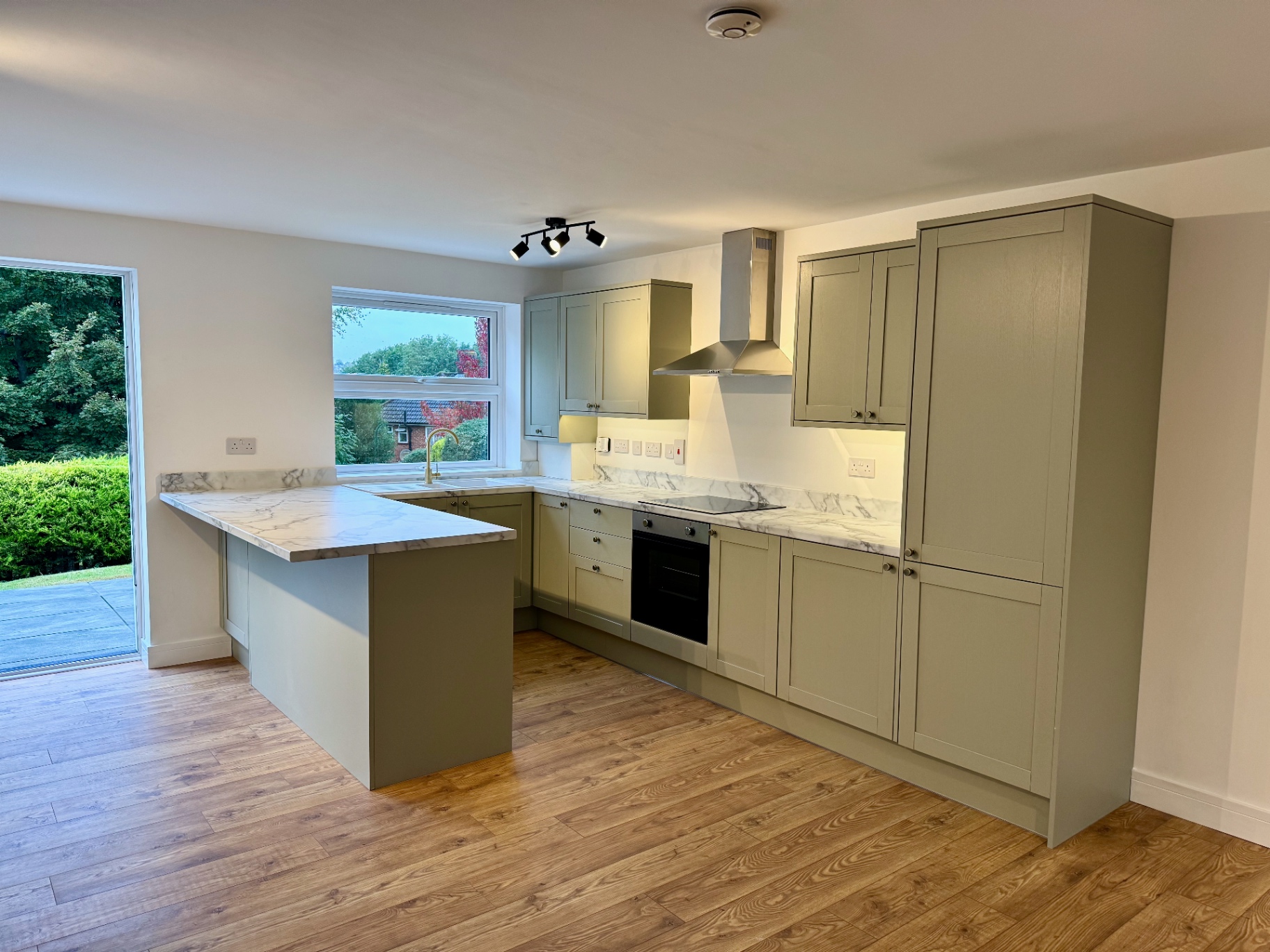Sage Shaker Kitchen — Cordrey Gardens Sage shaker kitchen with marble-effect peninsula, timber flooring and garden doors