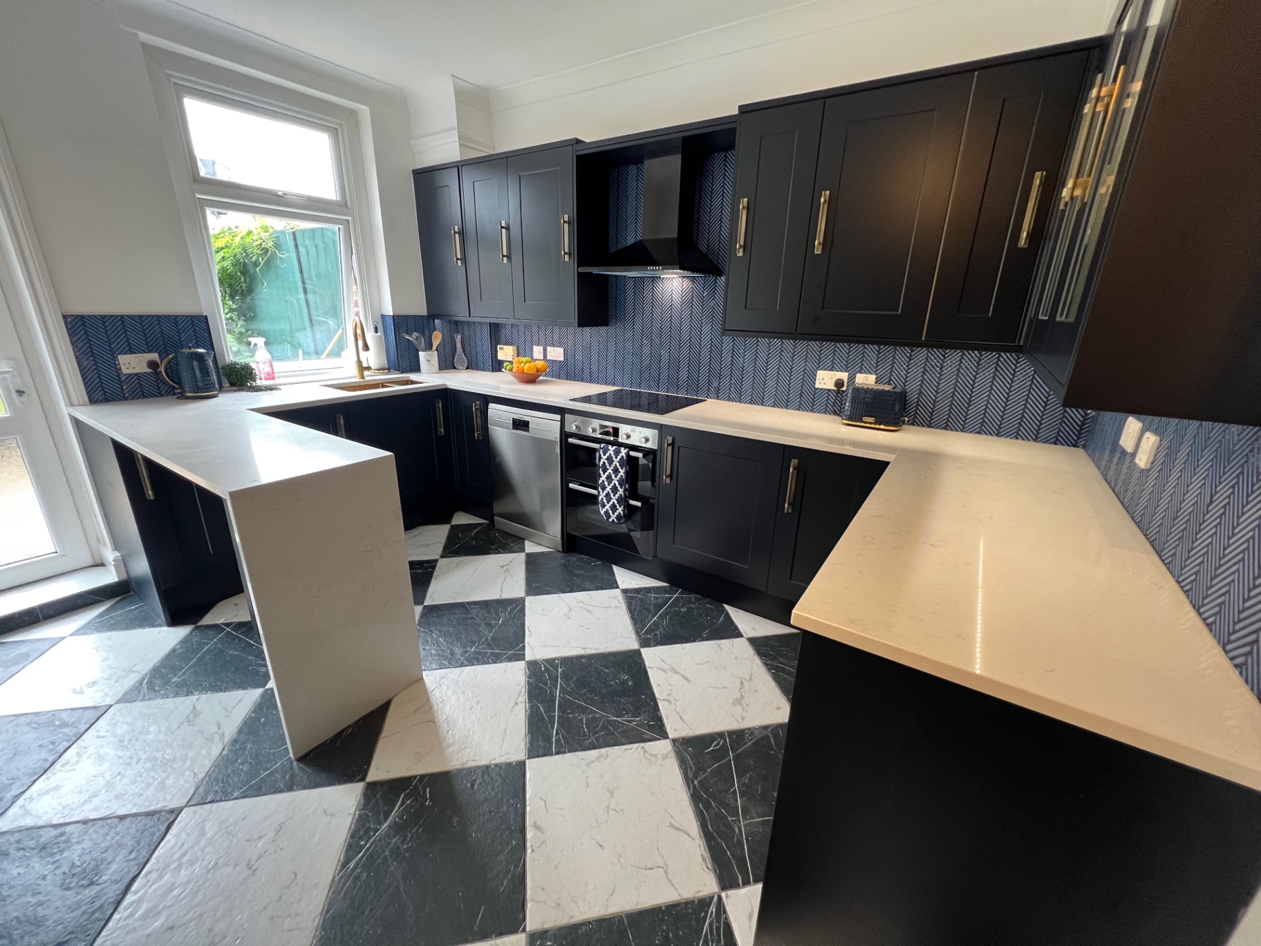 Wide view of the navy shaker kitchen with peninsula and herringbone splashback