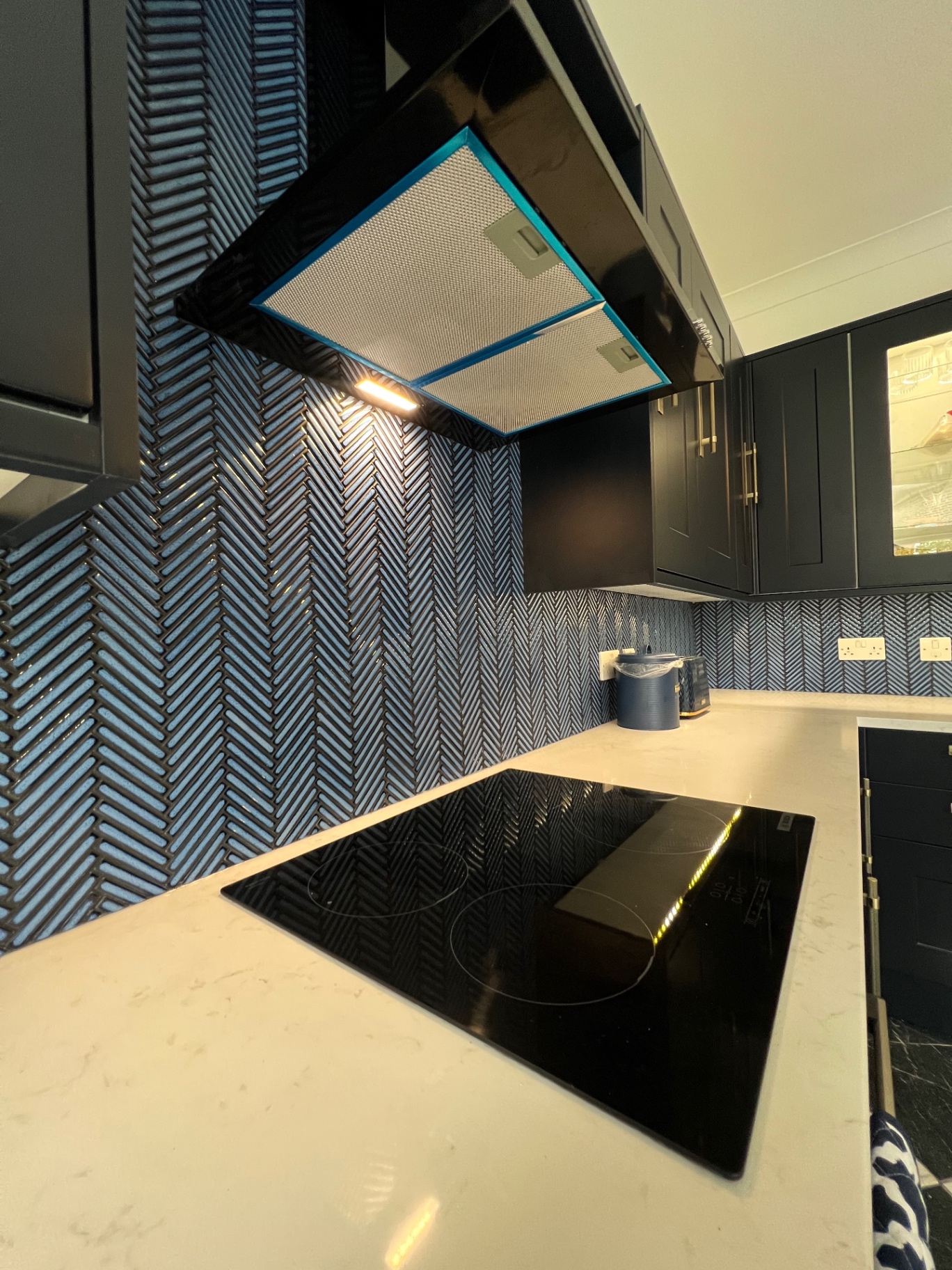 Blue herringbone tiled splashback behind the hob and extractor