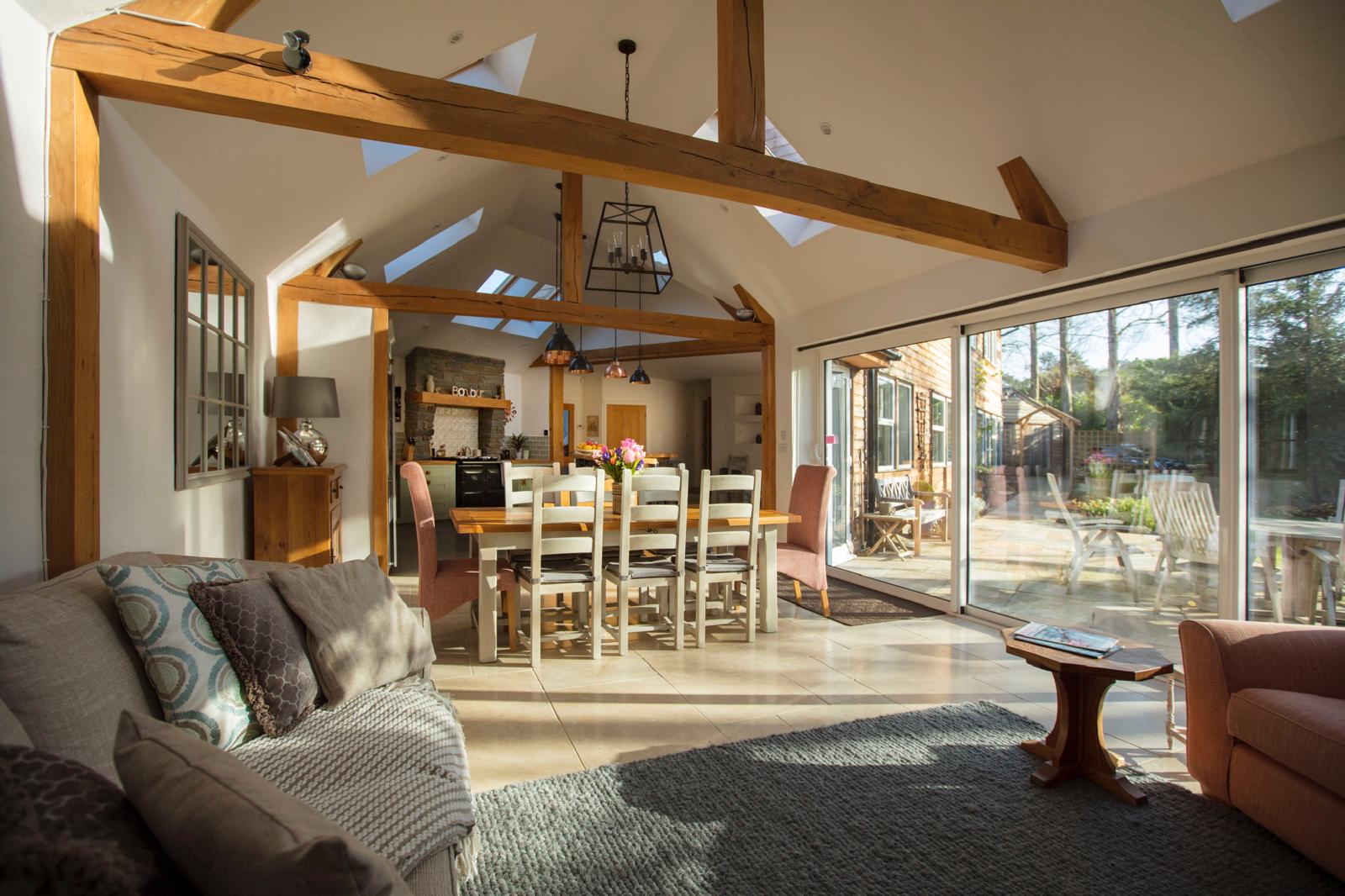 Open-plan living and dining space with exposed timber beams and garden glazing