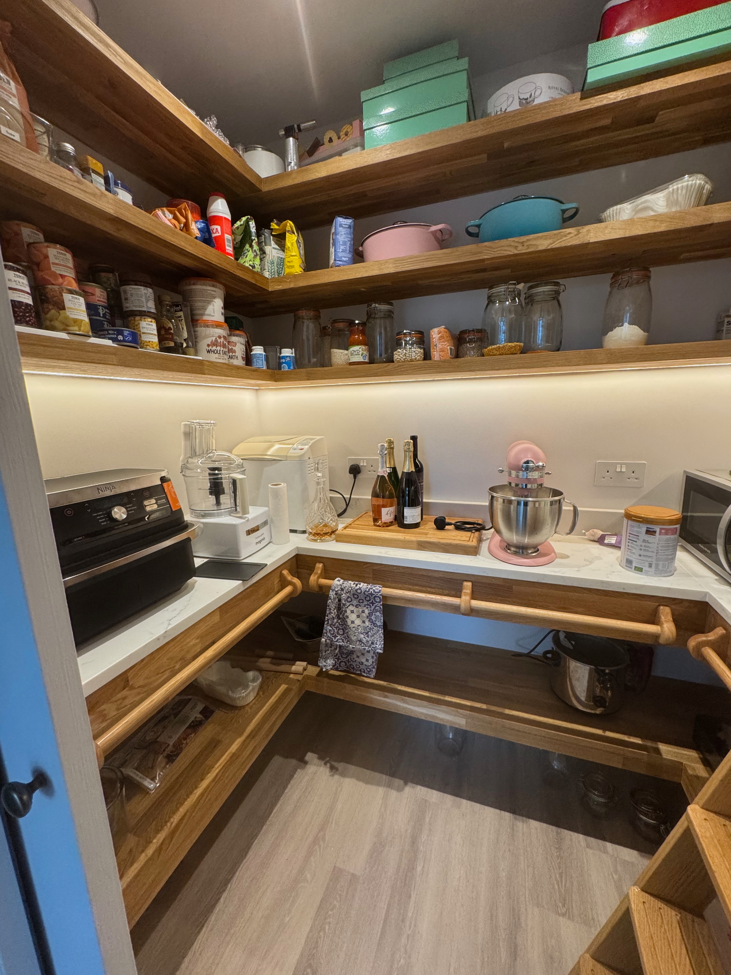 Walk-in pantry with oak shelving, worktop space and lit display shelves