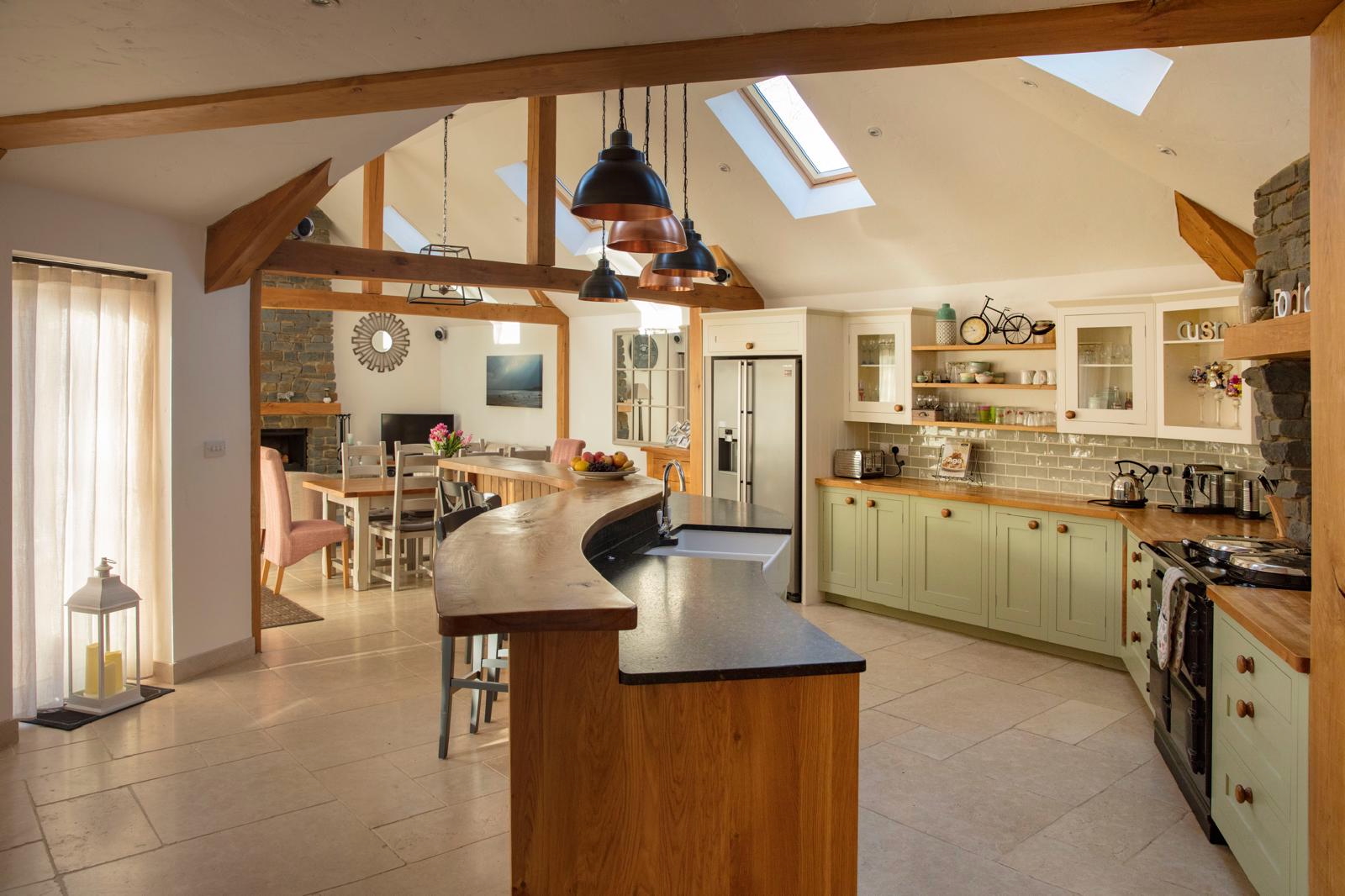 Open-plan kitchen with sage cabinetry, timber island and rooflights