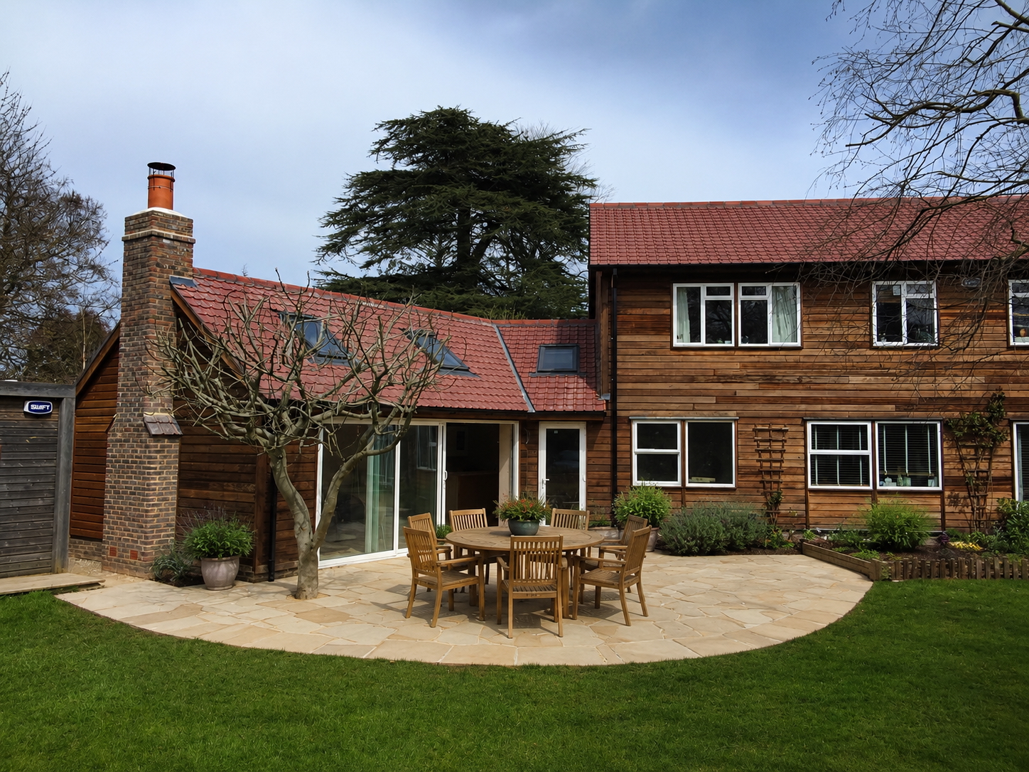 Completed timber-clad rear extension with tiled roof and sandstone patio
