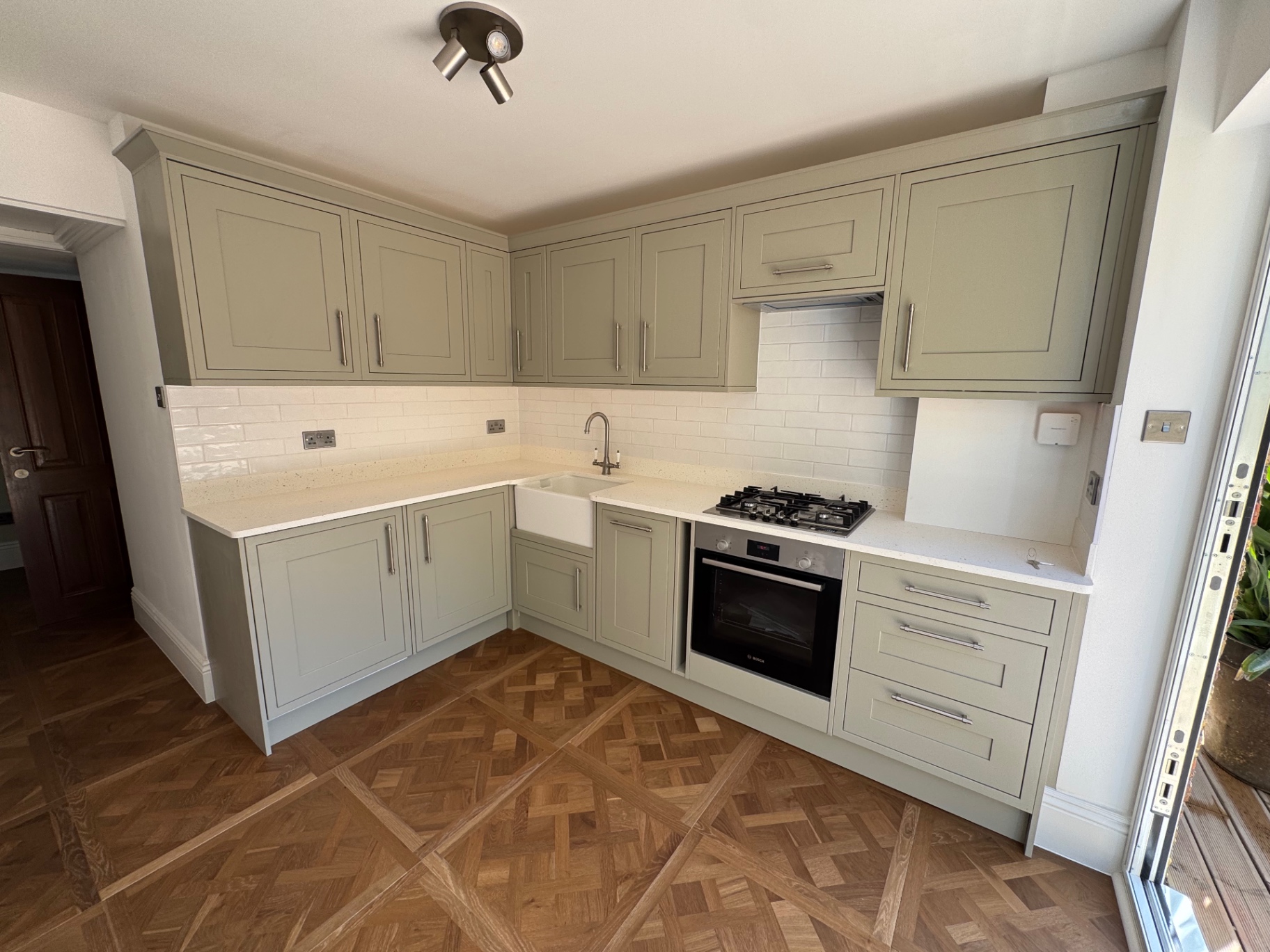 New sage shaker kitchen with quartz worktops, butler sink and metro tiled splashback